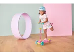 Smiling girl in a blue helmet on a pink Lupilu Tri-Scooter with LED wheels.