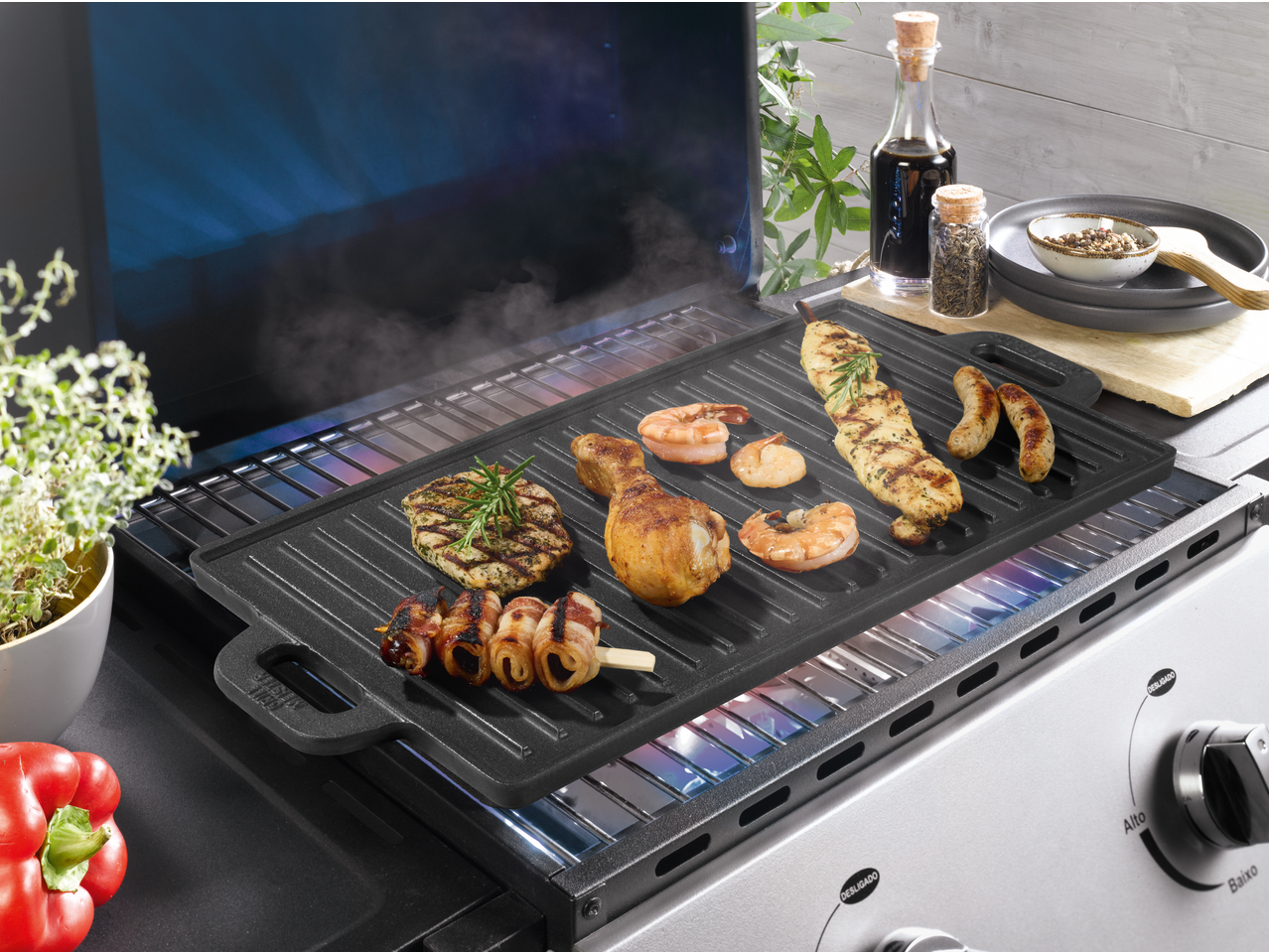 Grillmeister Cast Iron Grill Pan/Plate with various foods cooking on a gas grill.