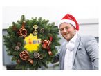 Christmas wreath and man in suit wearing a Santa hat.