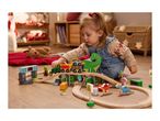 Toddler playing with a wooden dinosaur-themed train set on the floor.