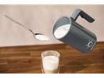 Uma colher de espuma de leite é despejada de um espumador de leite SilverCrest em um copo de café.