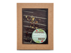 Een chocoladereep met matcha, cranberry en pistache in een kartonnen verpakking.