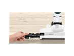 A hand removing the brush roller from a white Bosch cordless vacuum cleaner head on a wooden floor.