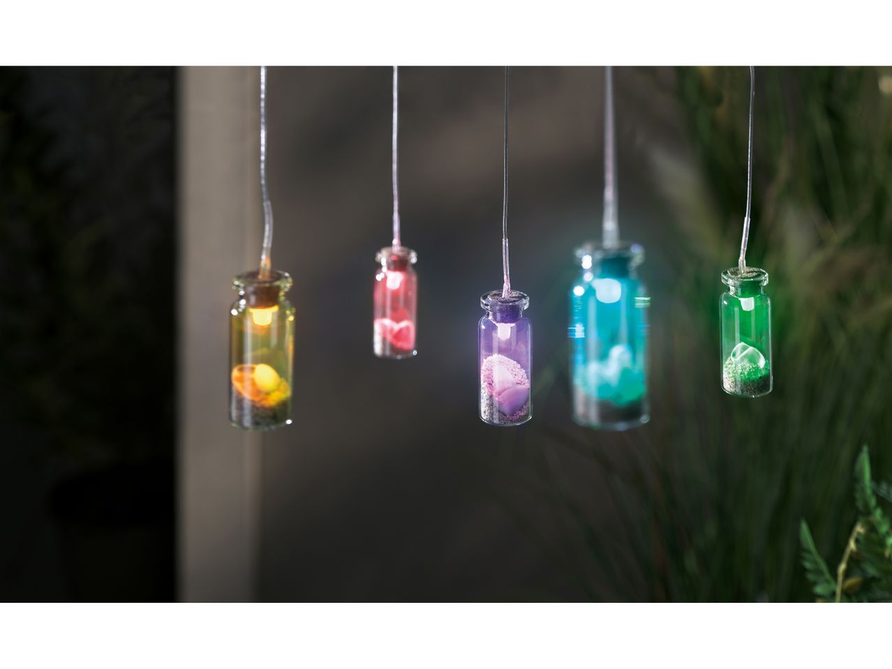 Colorful glass bottle ornaments hang from strings.