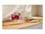 Pink patterned glasses with red currant drinks and fresh berries on a wooden countertop.