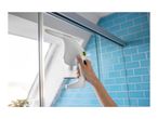 Handheld window vacuum cleaner cleaning a shower screen in a bathroom with blue tiles.