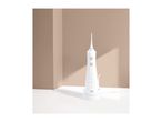 White oral irrigator with multiple settings on a white surface against a beige background.