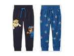 Zwei Jogginghosen für Kinder: eine dunkelblaue mit Paw Patrol-Motiv und eine blaue mit Sonic-Motiv.