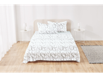 A bed with white sheets with a gray pattern, two nightstands with lamps, and a rug in a bedroom.