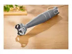 A SilverCrest immersion blender on a wooden surface with basil and cheese.