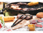 Grilled meat, sausages, and corn on a barbecue with condiments and bread.
