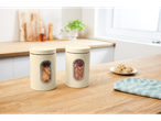 Two cream-colored kitchen canisters with clear windows, one holding cookies and the other dried flowers, on a wooden countertop.