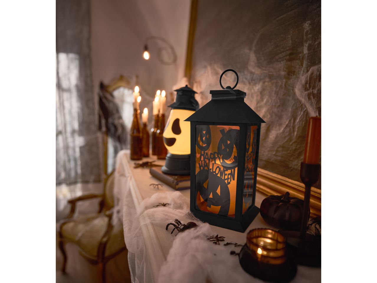 Lanterna di Halloween con zucche e ragnatele su un caminetto decorato.