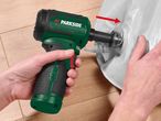 A person using a green and black power tool to inflate a white inflatable item.