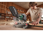 A man uses a Parkside miter saw to cut a piece of wood.