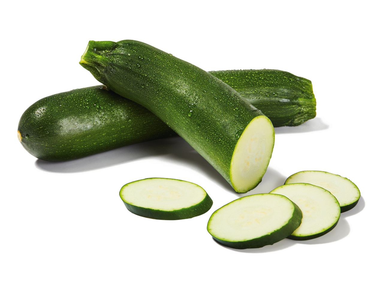 Courgettes fraîches entières et coupées en tranches, avec des gouttelettes d'eau.