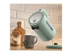 Mint green electric kettle pouring hot water into a grey mug with a tea bag.