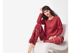 Woman in red fleece pyjamas with a snowflake pattern, sitting on a white chair.