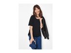 Woman in black t-shirt and jeans, holding a black leather jacket, smiling.