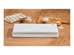 White vacuum sealer on a wooden table next to garlic, spices and a kitchen towel.