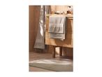 Bathroom with light brown towels, a wooden vanity, and a light green bath mat.