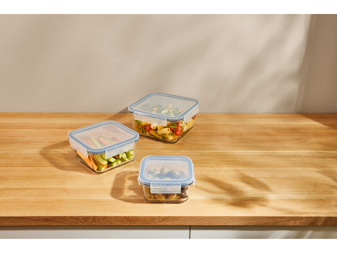 Recipiente din sticlă cu mâncare: salată, legume și măsline.