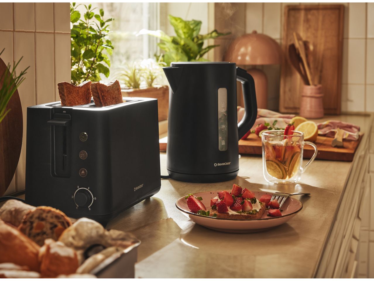 Silvercrest black kettle and toaster on kitchen counter with breakfast food.