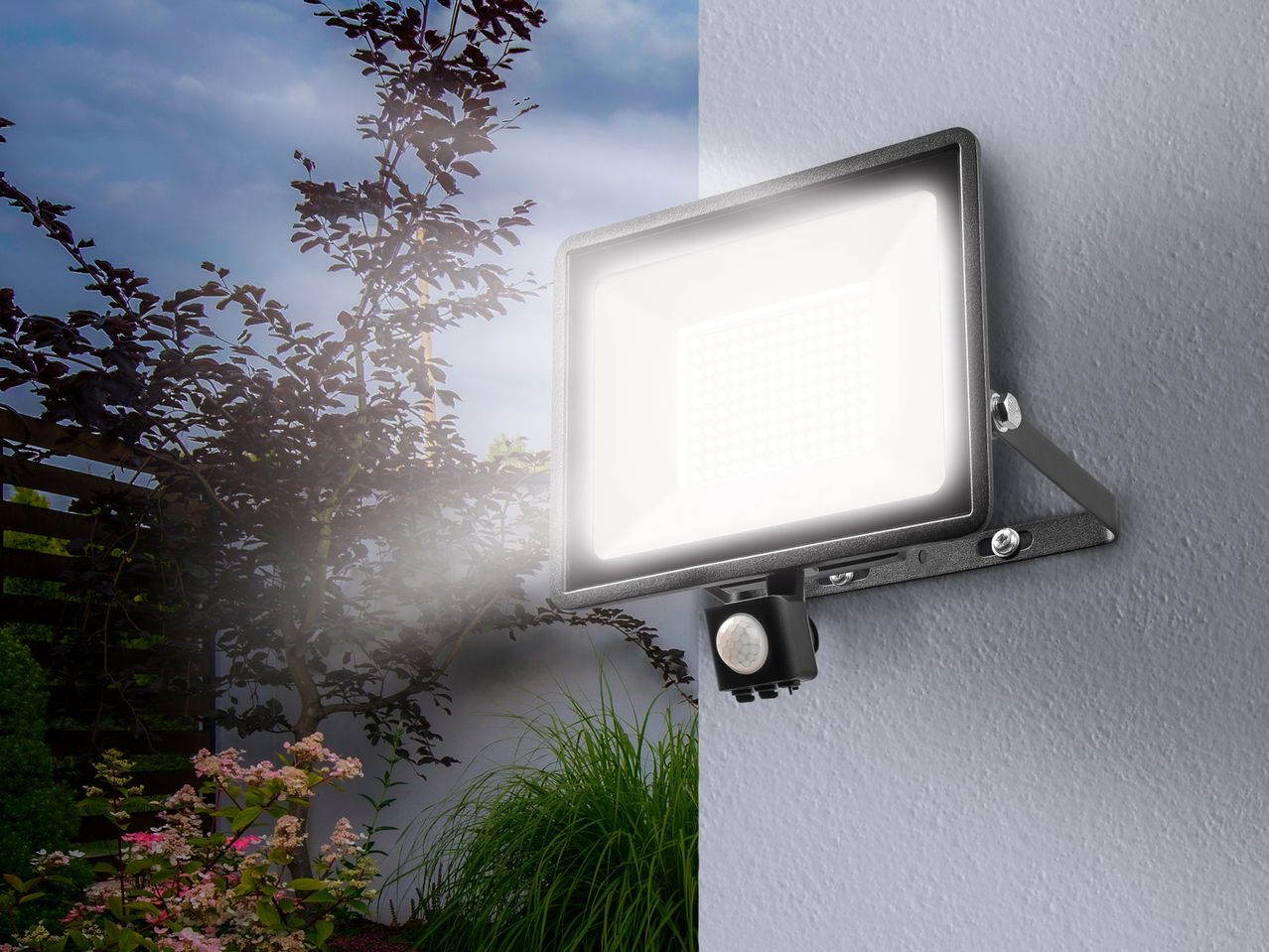 An outdoor LED Outdoor Light with a motion sensor mounted on a wall, illuminating a garden at dusk.