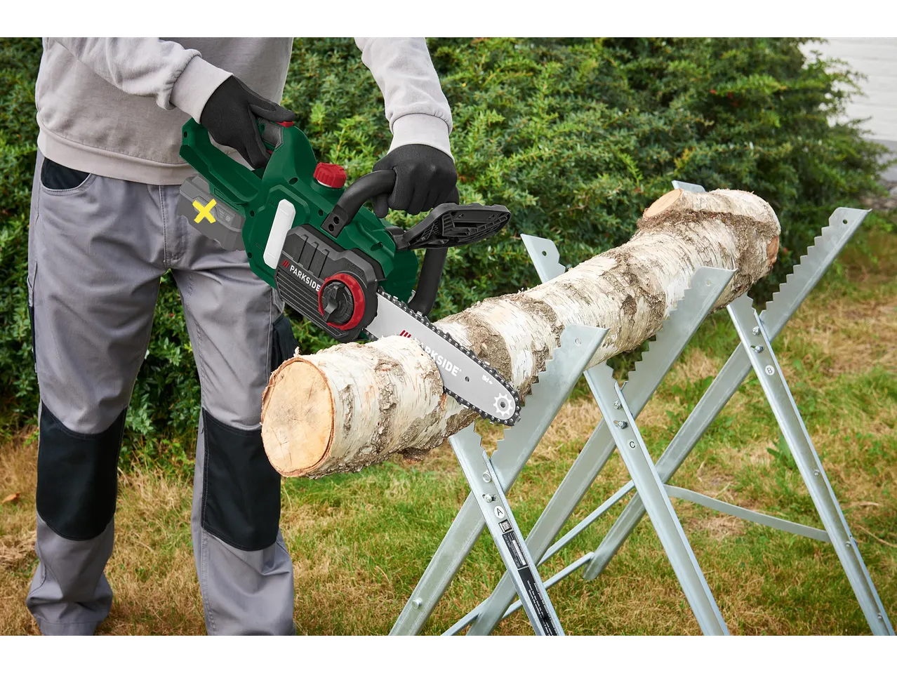 Person using a Parkside® 20 V cordless chainsaw to cut a log.