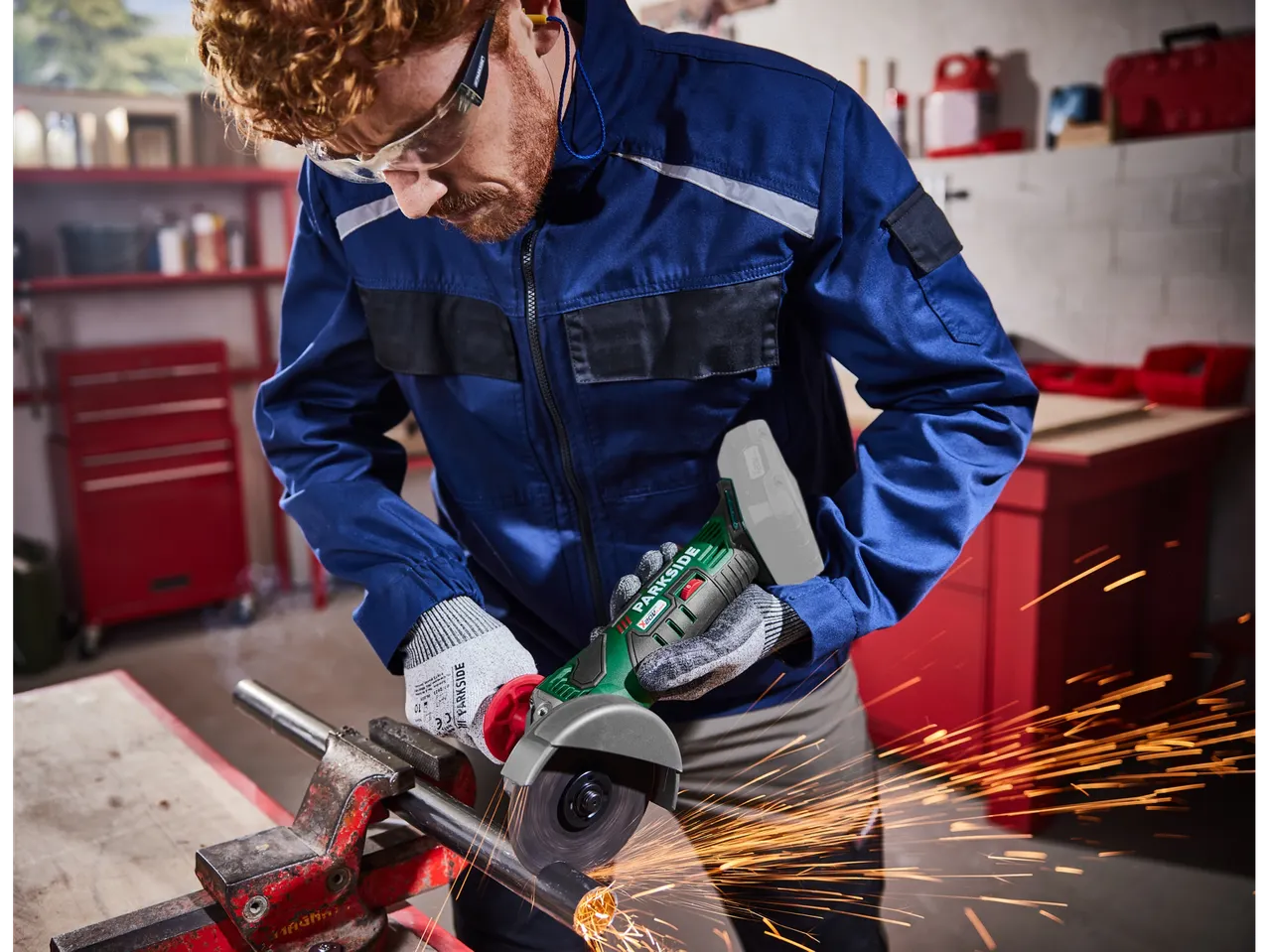A worker uses a Parkside angle grinder to cut a metal pipe.