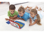 Trei copii stau întinși pe un covor și folosesc un laptop de jucărie albastru cu tema Paw Patrol.