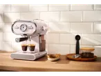 A pink SilverCrest espresso machine makes coffee in two cups on a wooden counter.