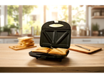 Un toaster pentru sandwich-uri pregătește două felii triunghiulare într-o bucătărie însorită.