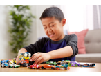 Smiling boy playing with a variety of Hot Wheels toy cars, including monster trucks and sports cars.