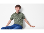 Model masculin purtând un polo cu imprimeu floral și blugi.