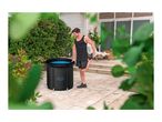 Man stretching next to an ice bath on a patio, surrounded by greenery.