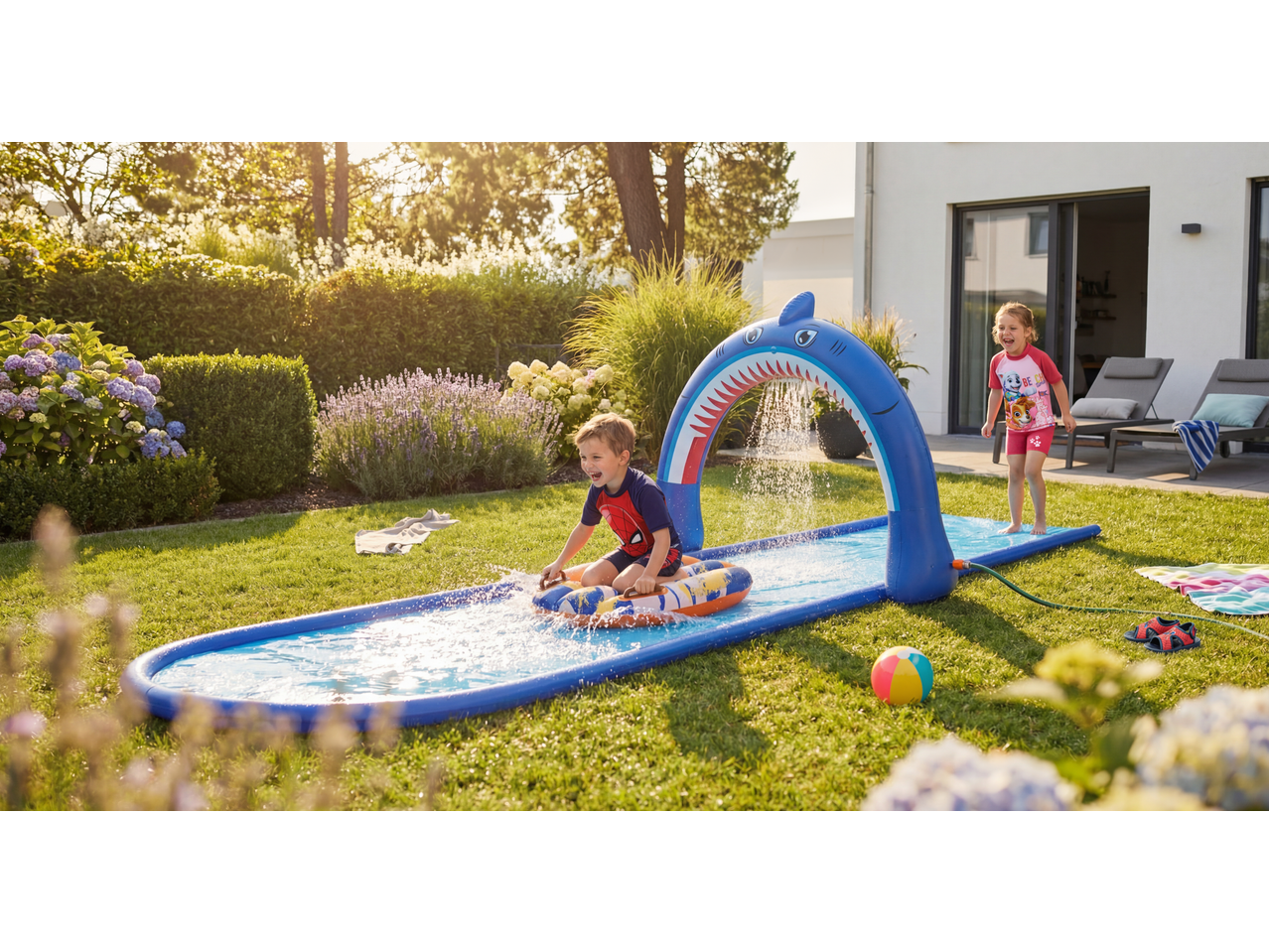 Lupilu water slide and paddling pool with children playing in a sunny garden.