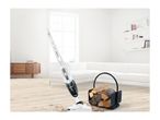 A Bosch cordless vacuum cleaner cleans up dirt near a wood basket in a modern living room.