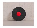 A black balance board with a red center, featuring the Crivit logo, against a textured wall.