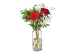 Gérberas vermelhas, rosa e gypsophila em um vaso de vidro.