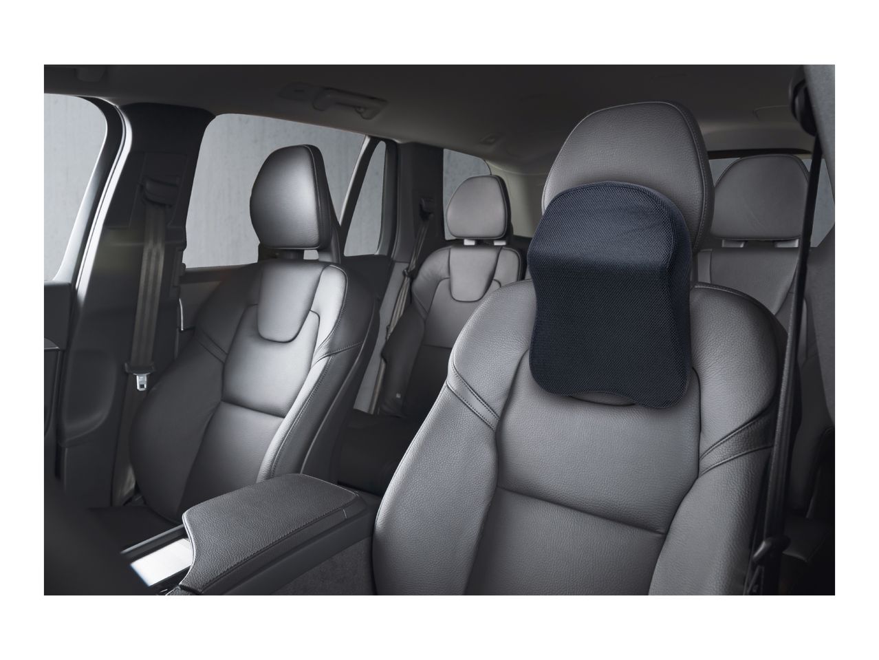 Car interior with black leather seats and a black mesh headrest pillow on the front passenger seat.