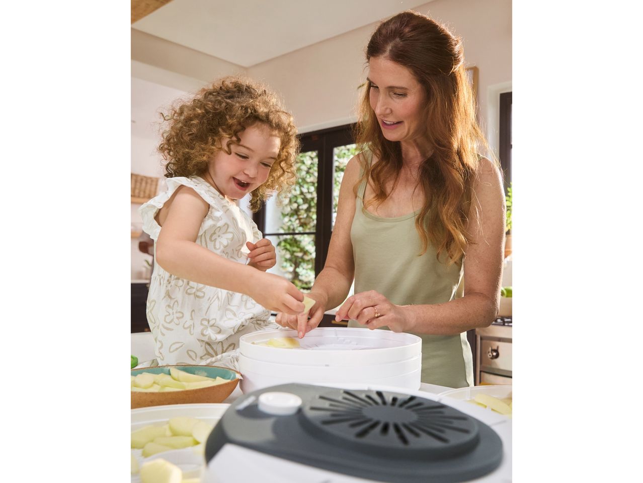 Una mamma e una bambina in cucina usano un essiccatore per alimenti