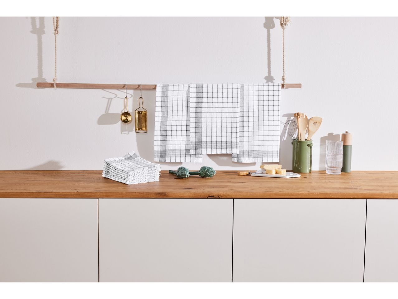 Serviettes de cuisine, ustensiles en bois et vaisselle.