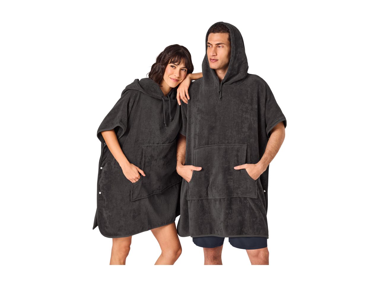 Two people in dark grey hooded changing ponchos, one with hands in the front pocket.