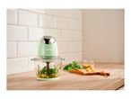 A SilverCrest food chopper with basil, pine nuts, and cheese on a wooden counter.