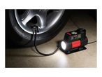 ULTIMATE UMK 10 E4 mini-compressor inflating a car tire in a dark setting.