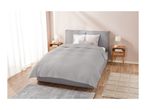 A modern bedroom with a grey upholstered bed, light grey quilted bedspread, and wooden nightstands.
