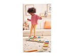 Child playing on a colorful balance beam set on a rug in a living room.