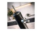 Black beverage dispenser with chrome tap in a modern kitchen setting.
