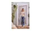 Woman in a t-shirt and jeans standing in a doorway with a magnetic fly screen.